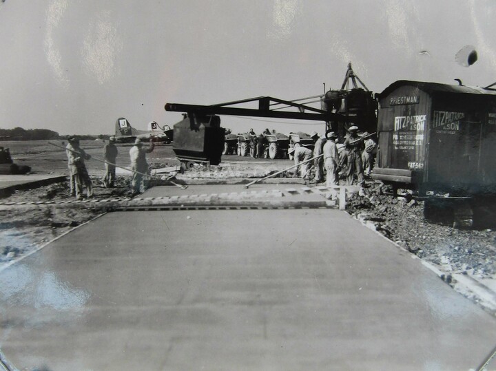Men from the 827th operate the paving machine at Framlingham while B-17 Flying Fortresses of the 390th Bombardment Group (note the Square 'J' on the tails) stand ready in the background for another mission.